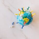 A globe decorated with colorful push pins on a marble surface represents global connections